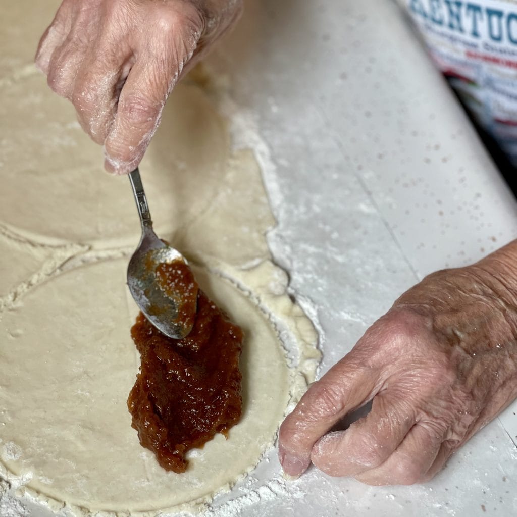 spreading the cooked apple filling into the dough for the fried apple pies