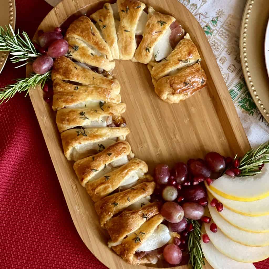 This is a picture of a crescent roll filled with brie, prosciutto, jam and melon in the shape of a candy cane.