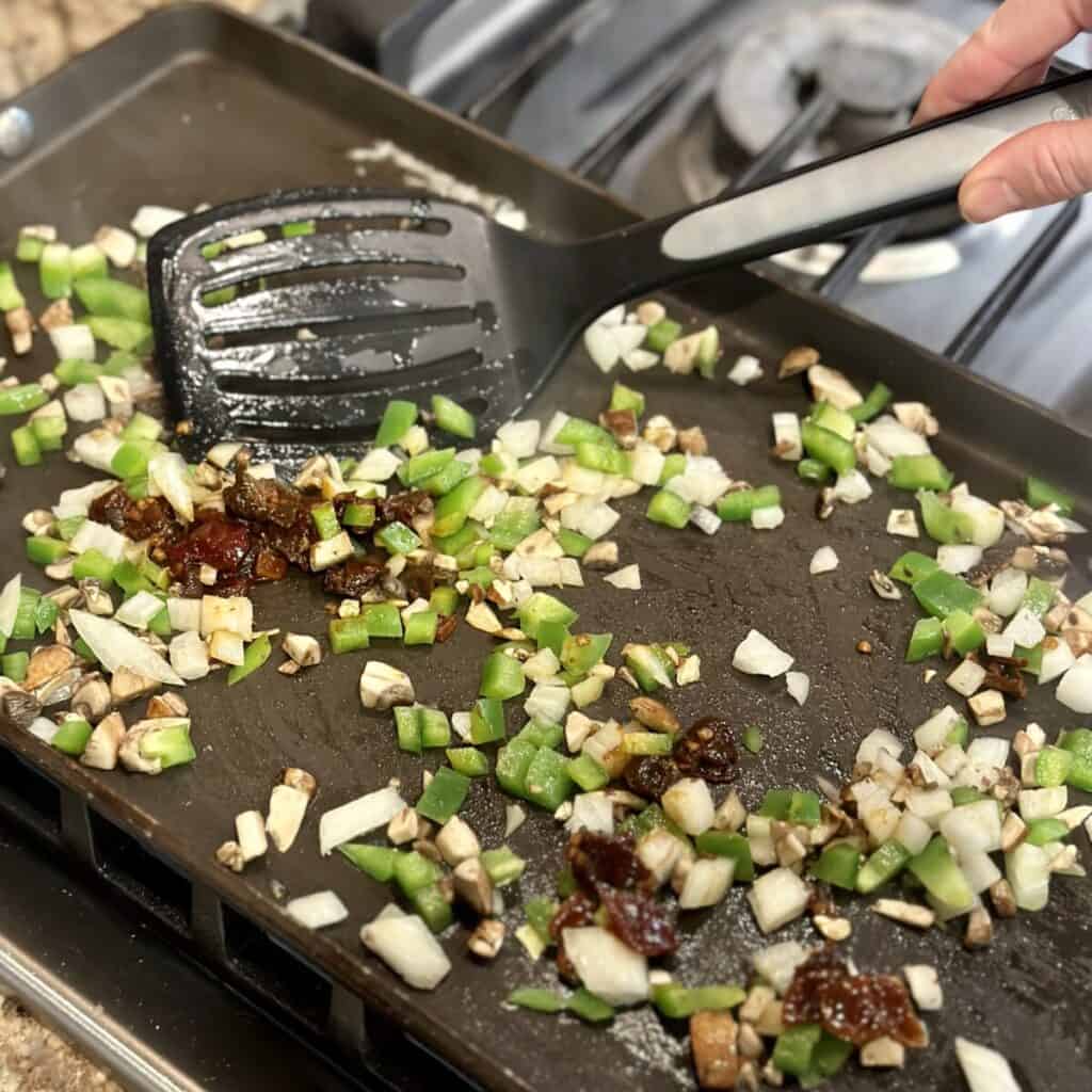 Sautéing vegetables on a griddle.