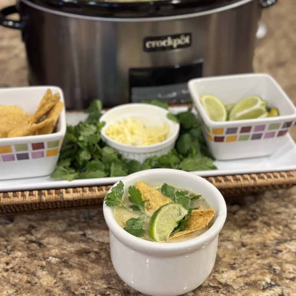 A bowl of soup next to a crockpot.