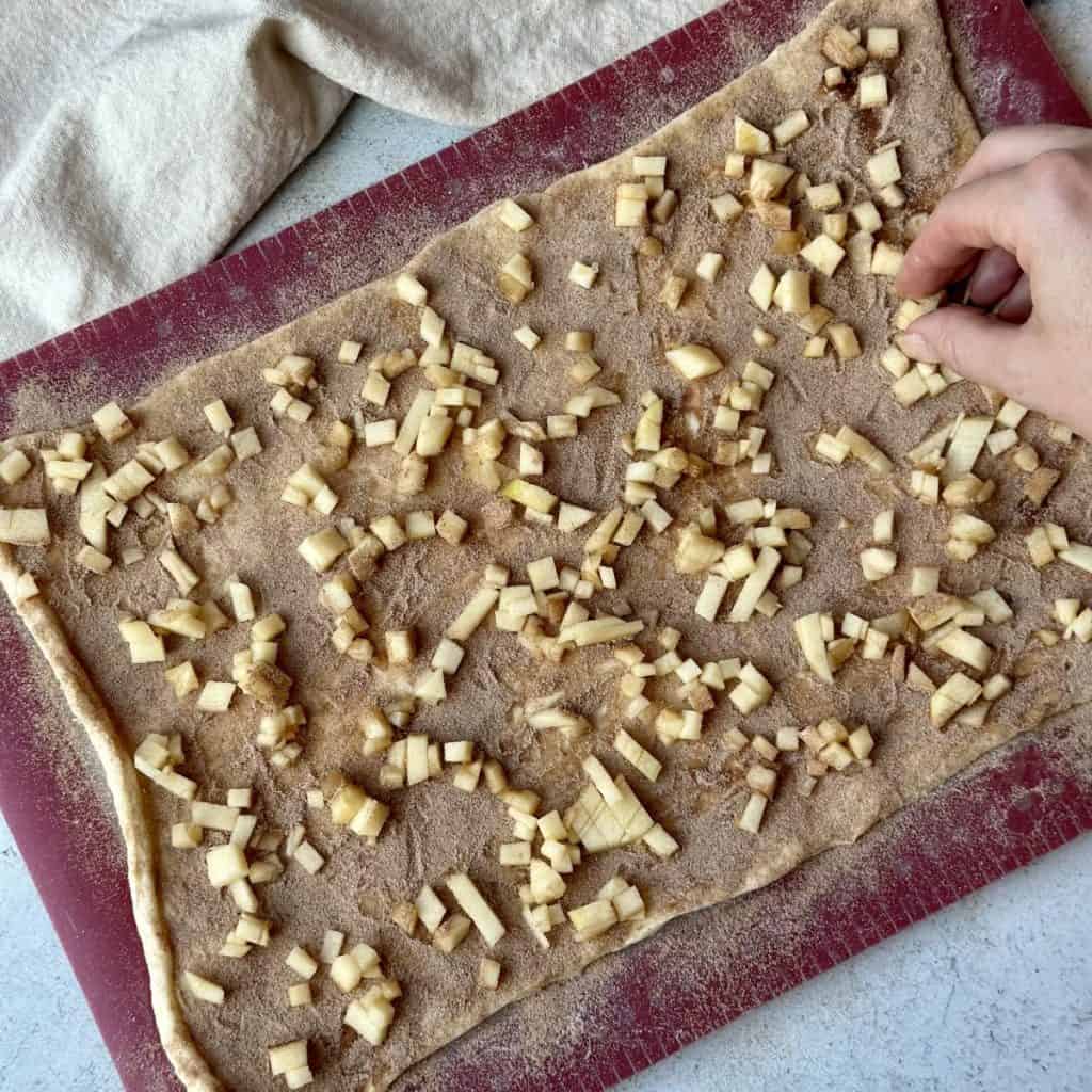 Adding chopped apples on cinnamon sugar dough.