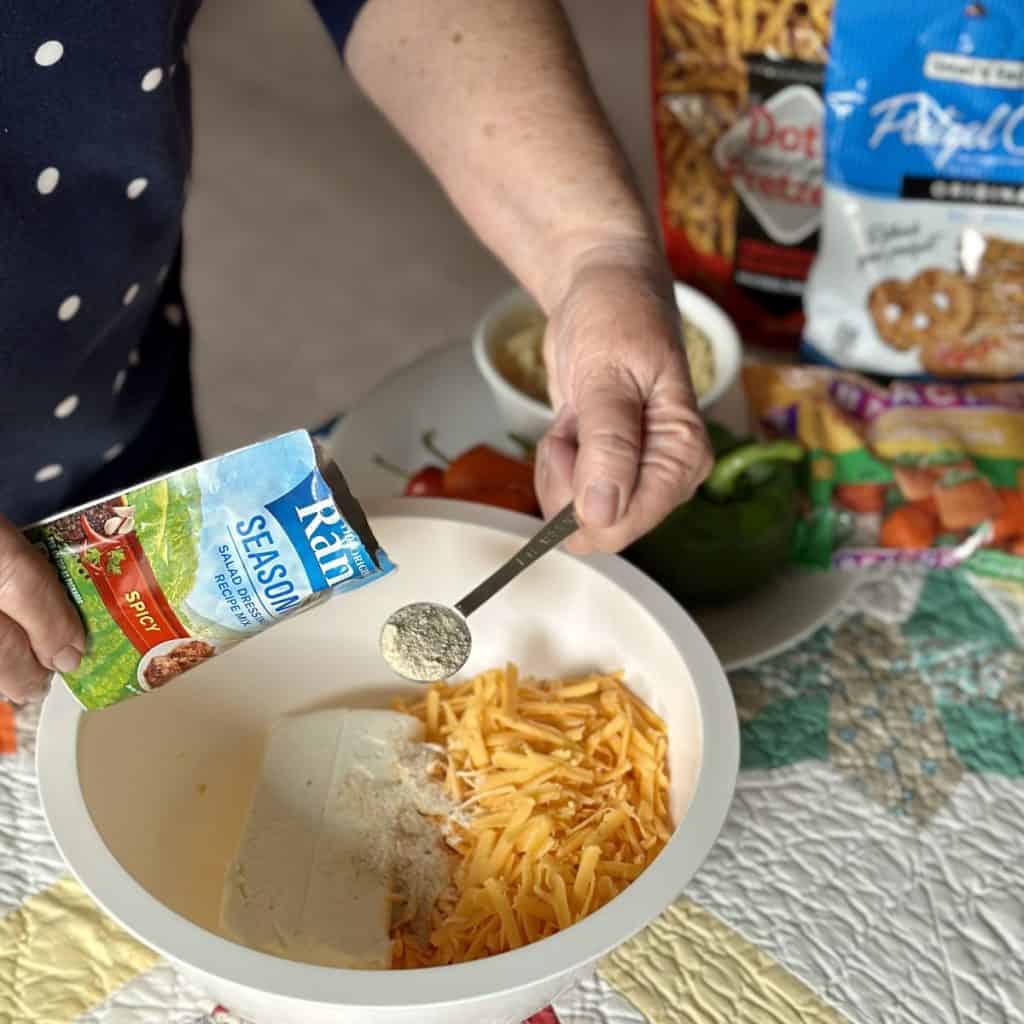 Adding seasoning powder to a cheeseball mixture.