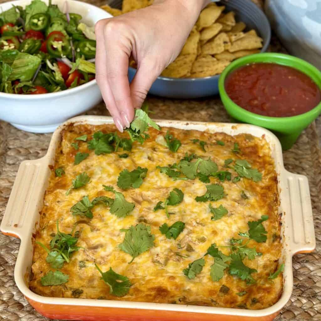 Adding cilantro to the top of Mexican lasagna.