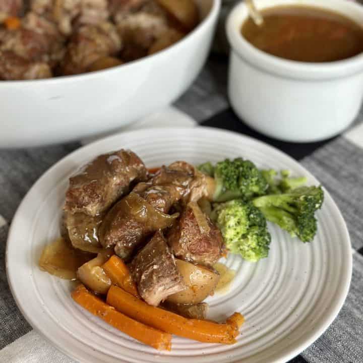 A plate of country style ribs with veggies.