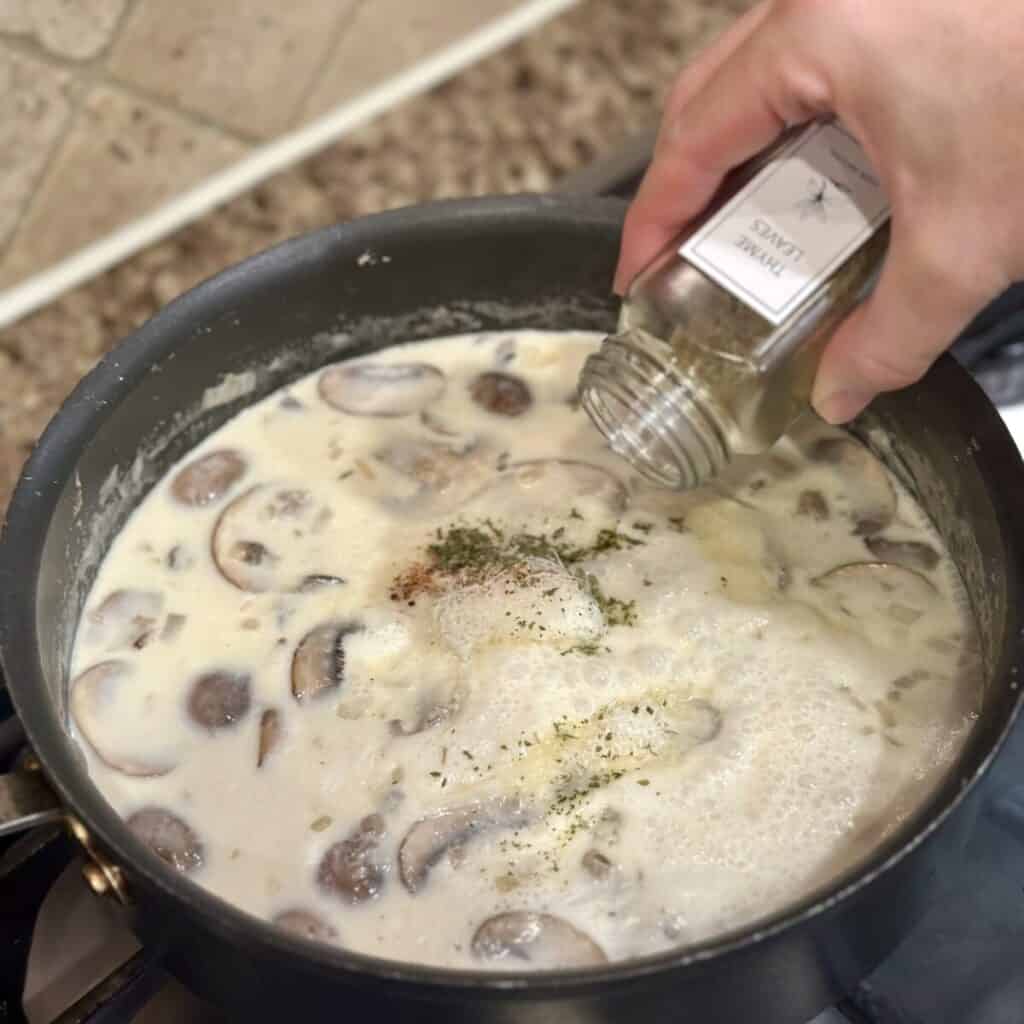 Adding seasoning to the filling of turkey tetrazzini in a pan.