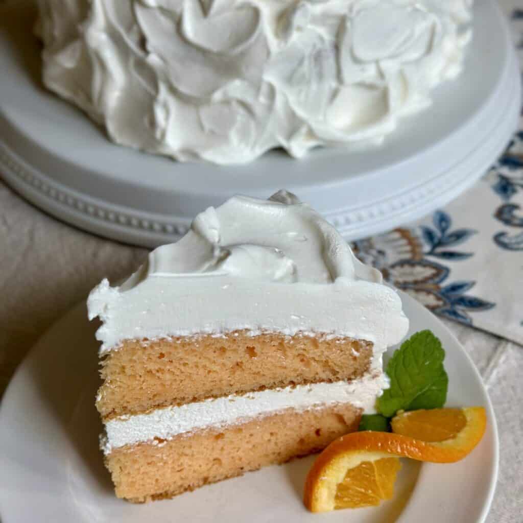 A slice of orange cake on a saucer.