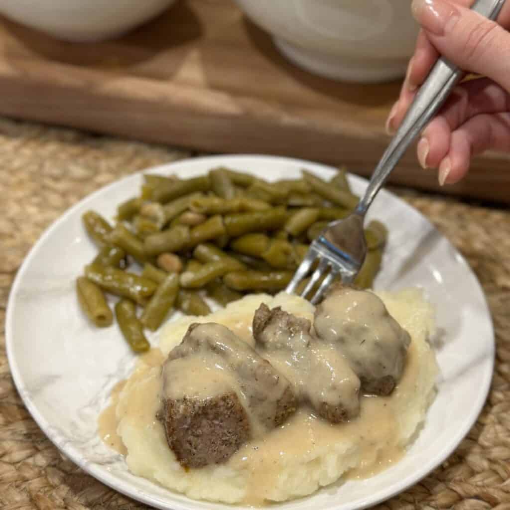 Getting a fork bite of pork tenderloin bites and gravy.