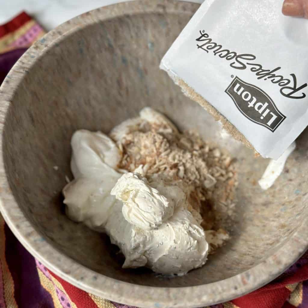 Adding ingredients for onion dip in a bowl.