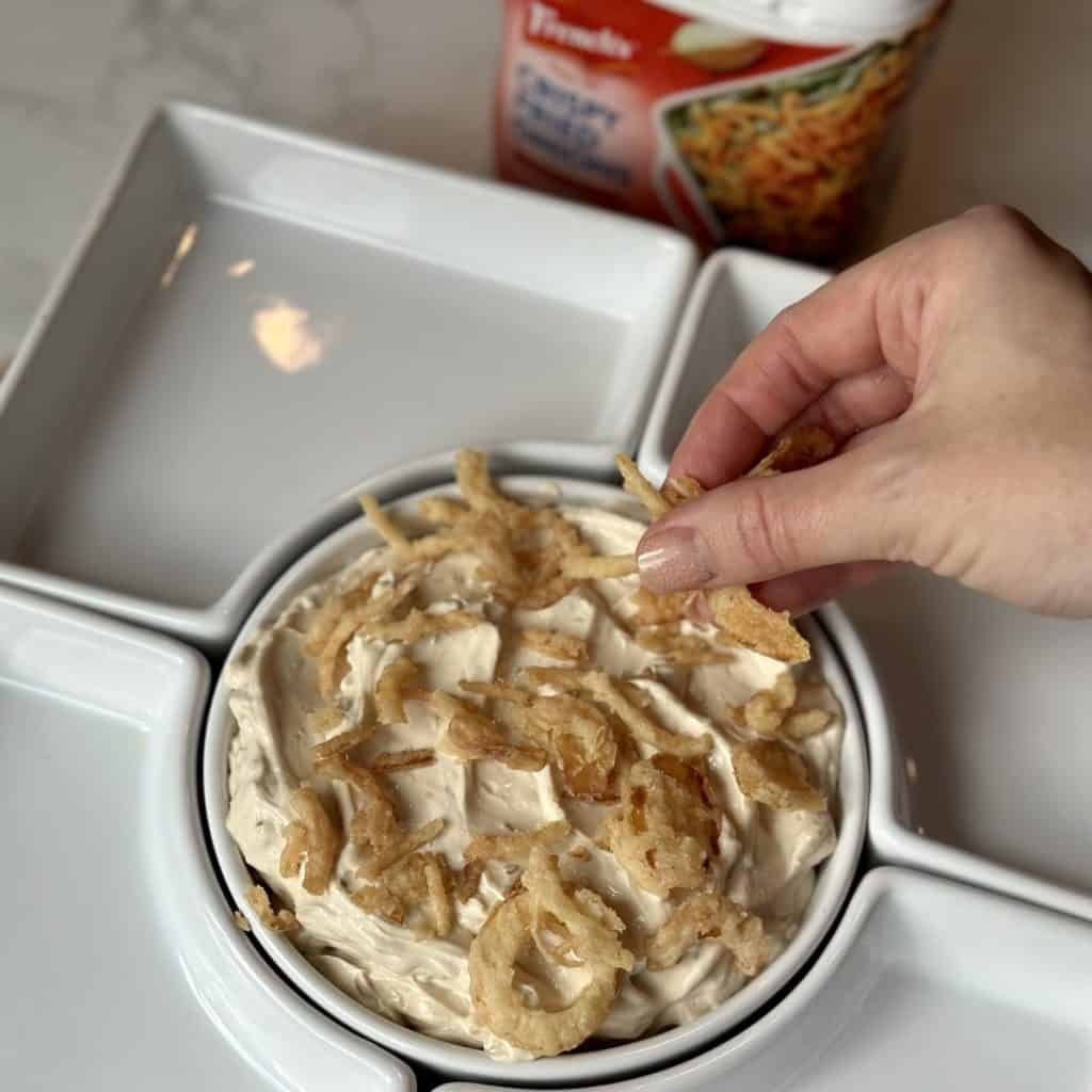 Adding onions to the top of a dip.