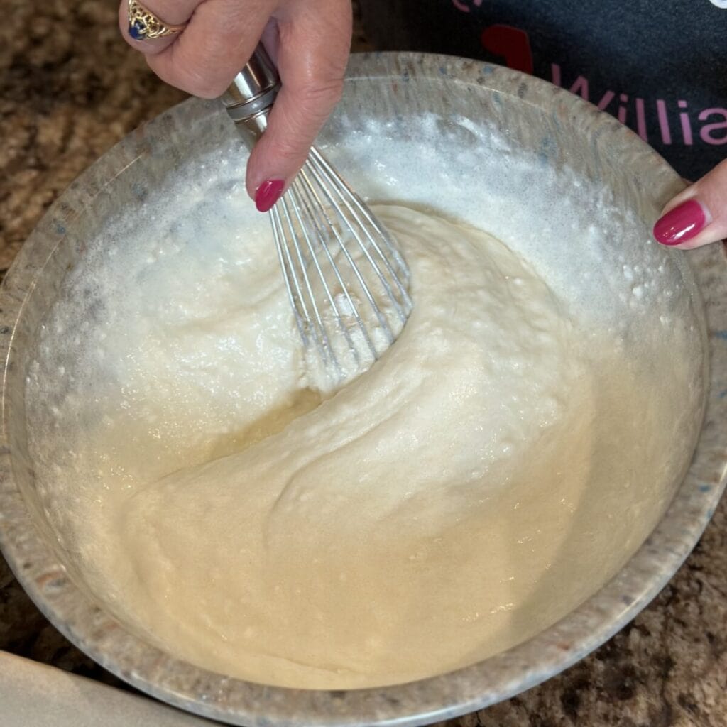 Whisking cobbler batter in a bowl.