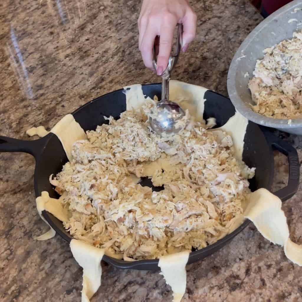 Adding chicken stuffing to a crescent roll ring.