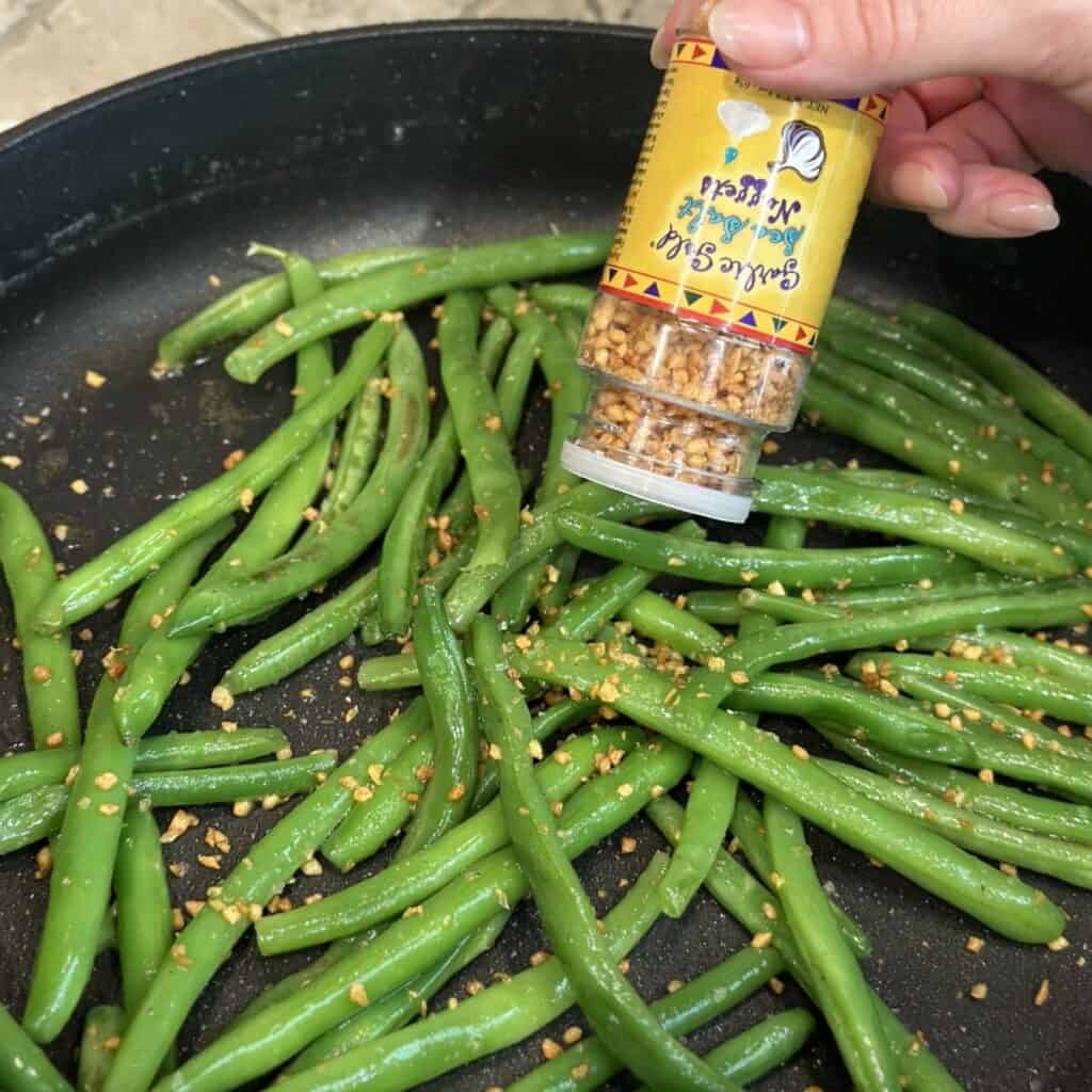 Adding crispy garlic to green beans.