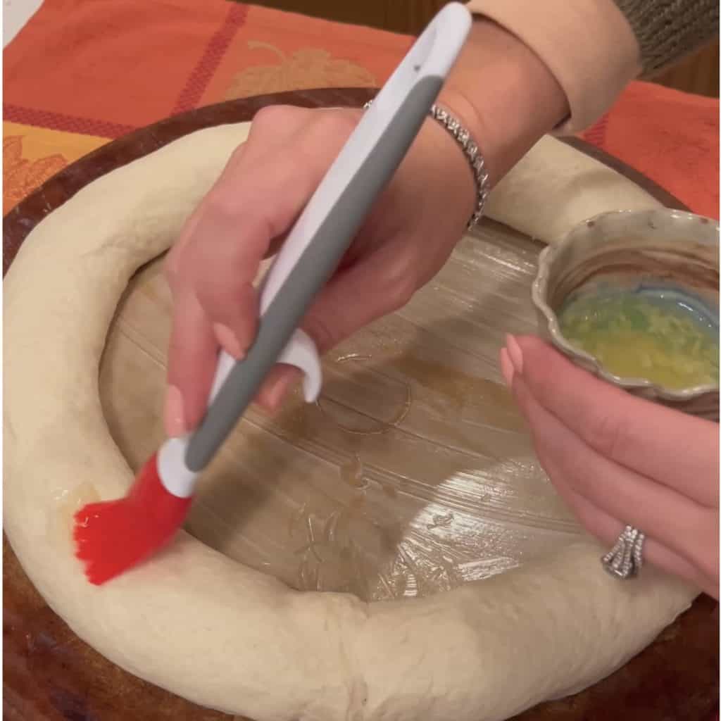 Brushing bread with an egg and garlic wash.