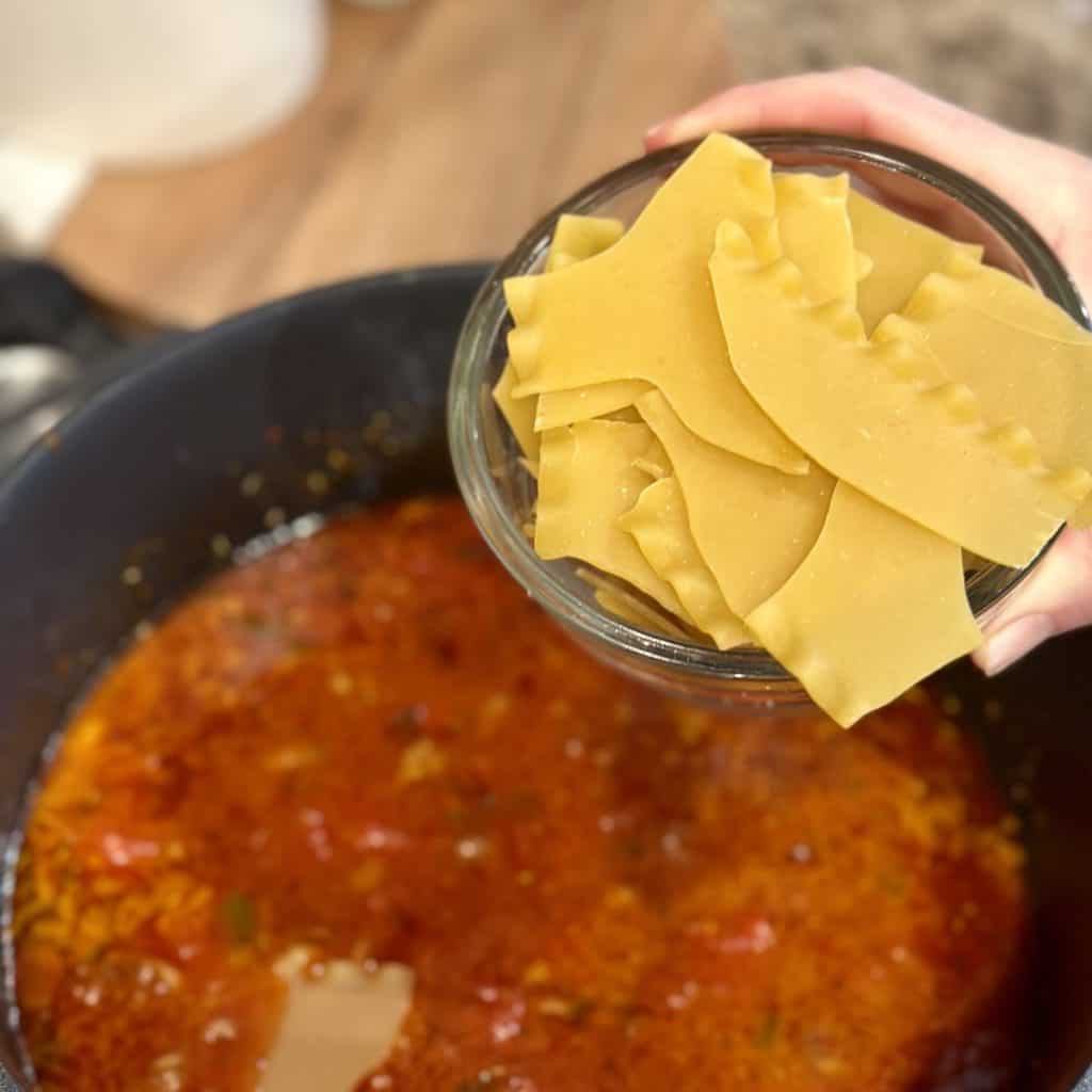 Adding lasagna noodles to soup.