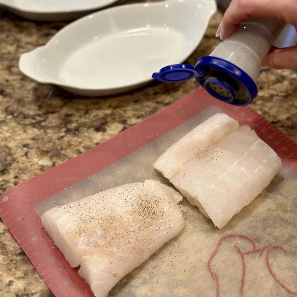 Seasoning cod with salt and pepper.