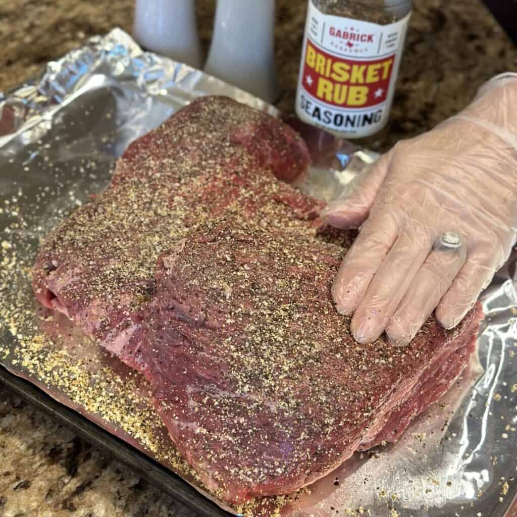 Pressing seasoning into brisket.