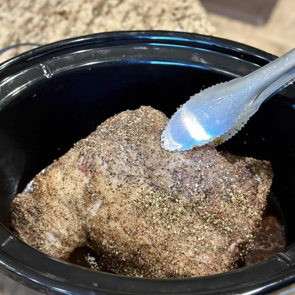 Adding brisket to a crockpot.