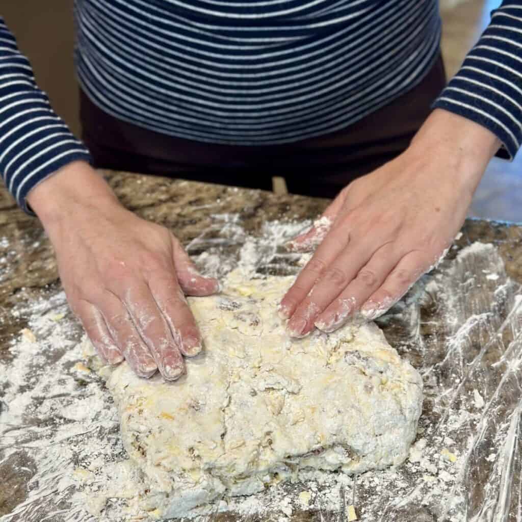 Pressing biscuit dough on a coutertop.