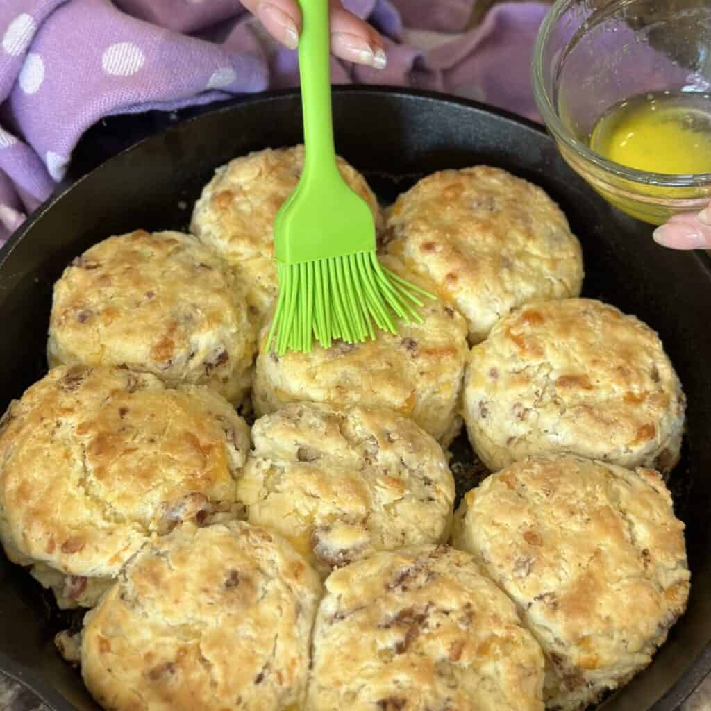 Brushing butter on baked biscuits.