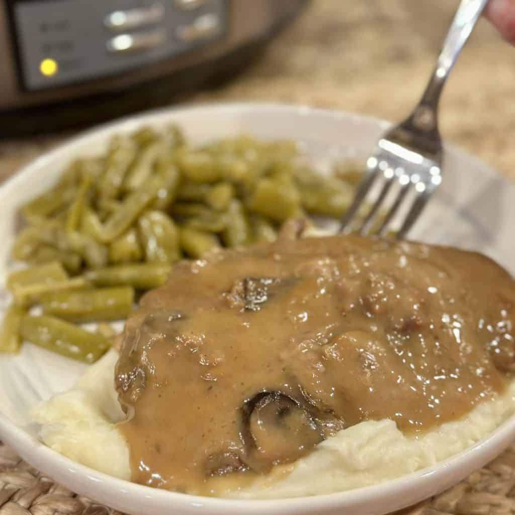 Cube steak, mashed potatoes and green beans on a plate.