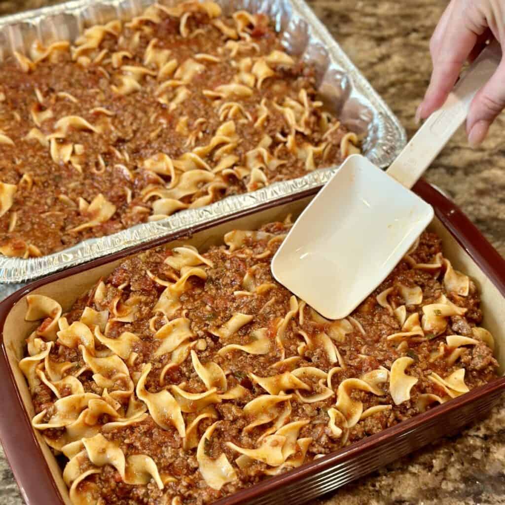 Spreading lasagna in a baking dish.