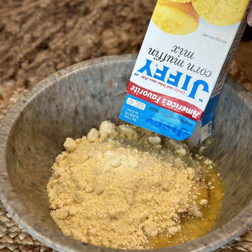 Adding ingredients for cornbread in a bowl.