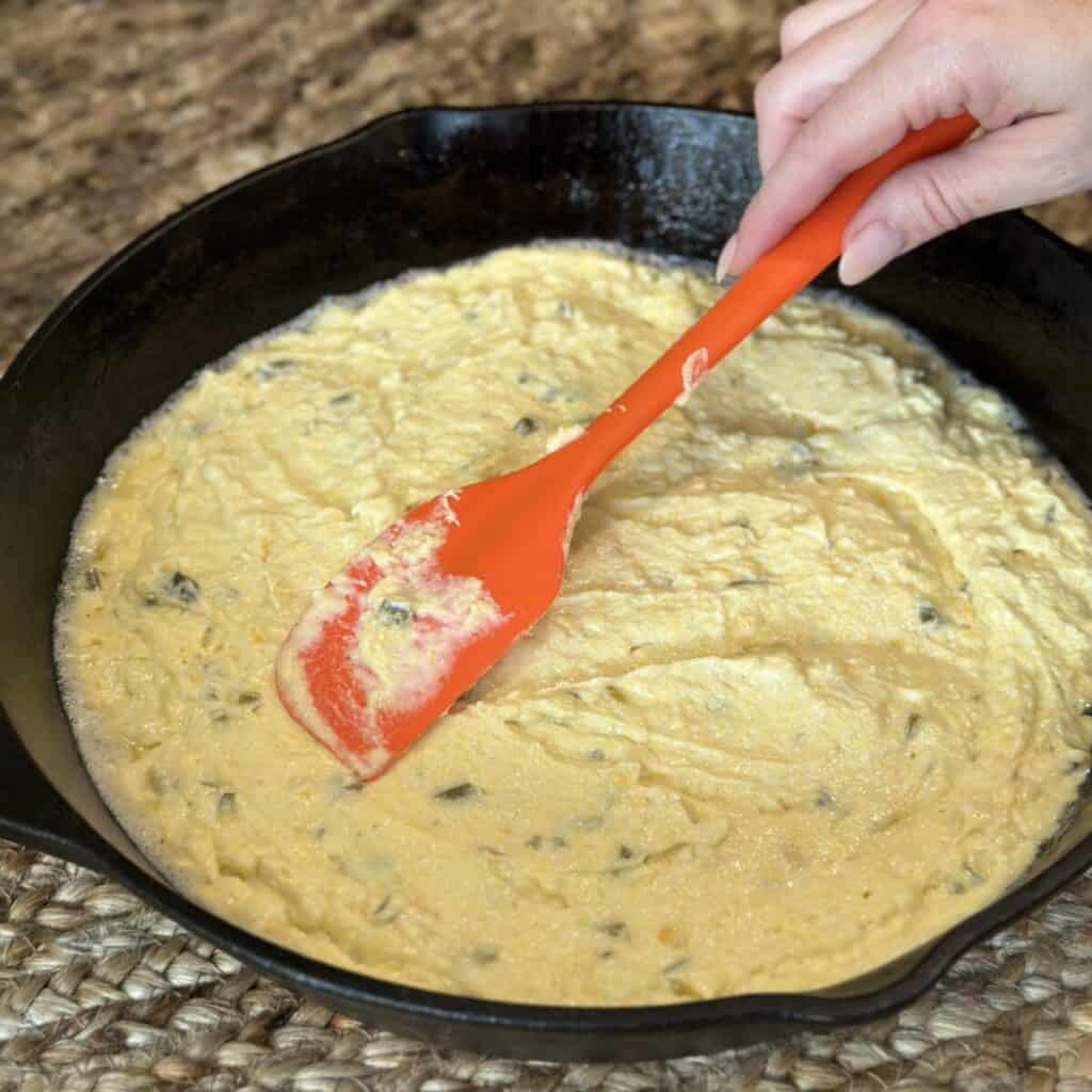 Spreading cornbread in a skillet.