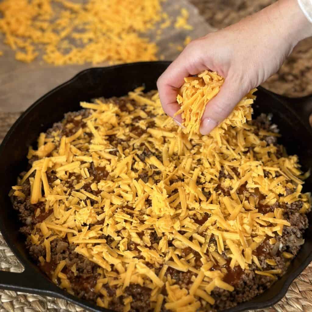 Adding cheese to the top of beef.