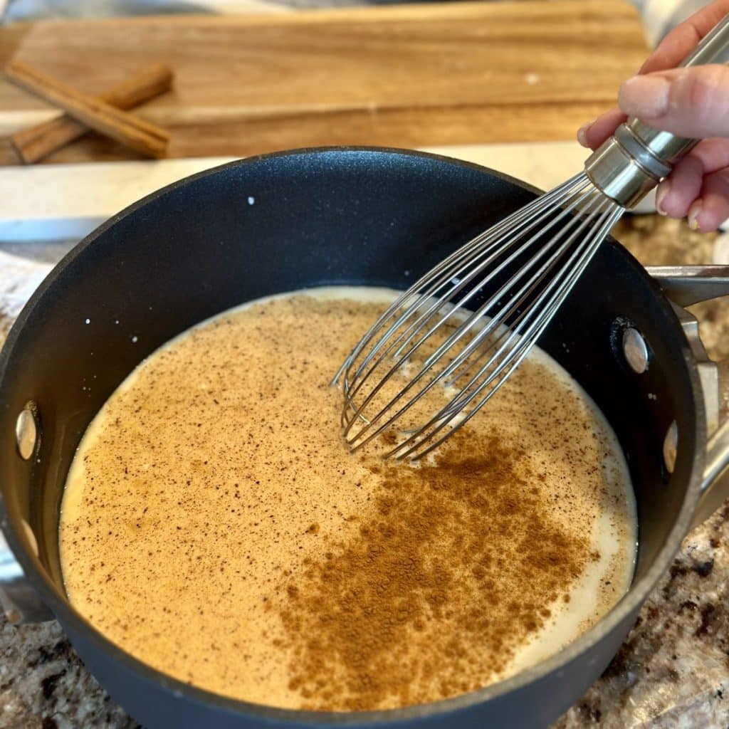 Whisking a vanilla cinnamon cream in a saucepan.