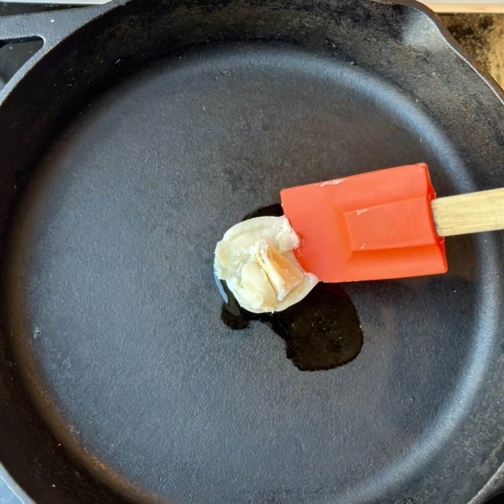 Adding bacon grease to a skillet.