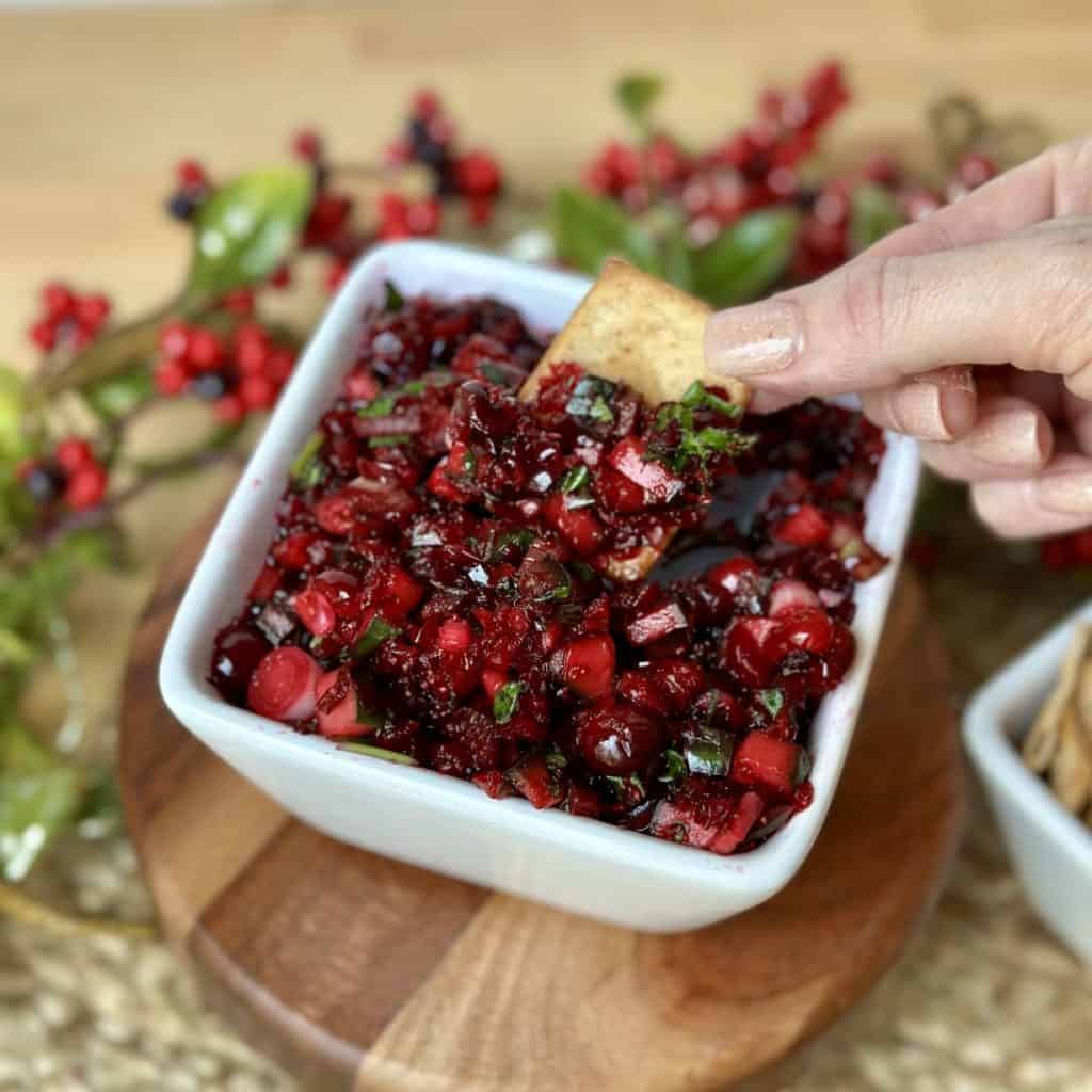 Scooping cranberry salsa with a cinnamon tortilla chip.