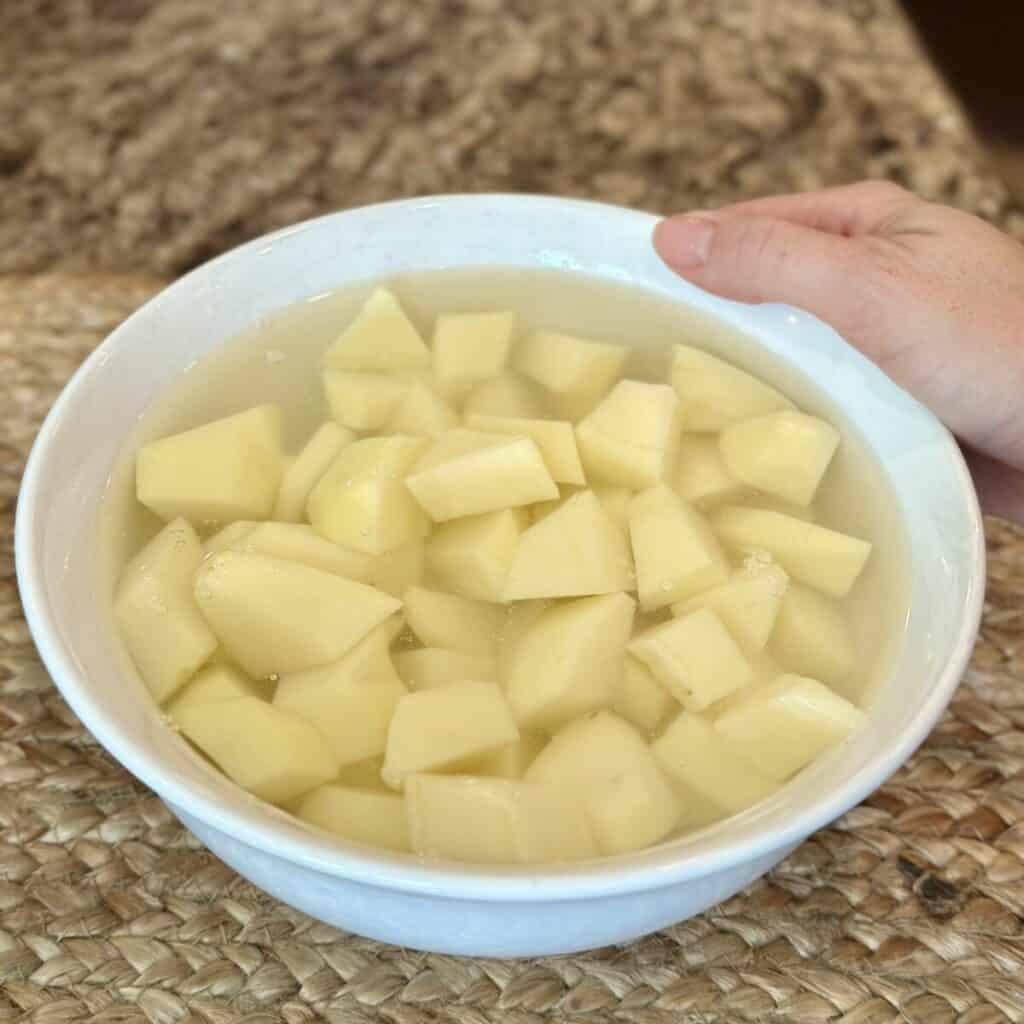 A bowl of potatoes soaking in water.