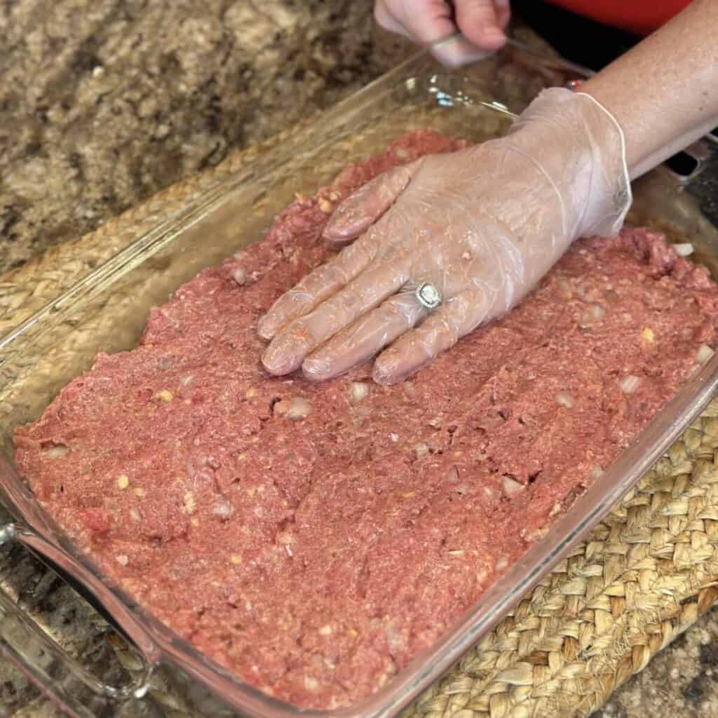 Pressing meatloaf in a baking dish.