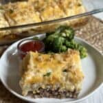 A serving of meatloaf casserole on a plate with broccoli.