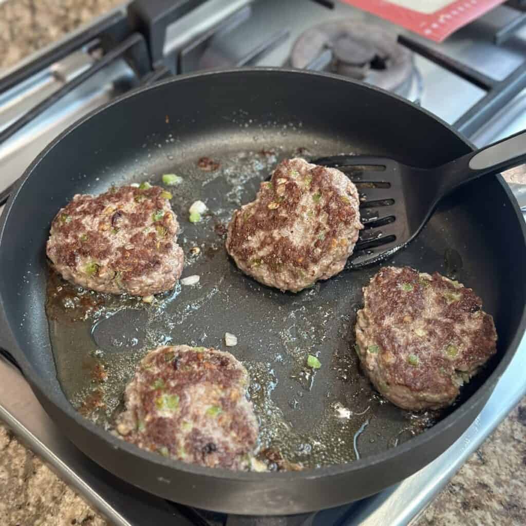 Flipping Salisbury steaks in a skillet.