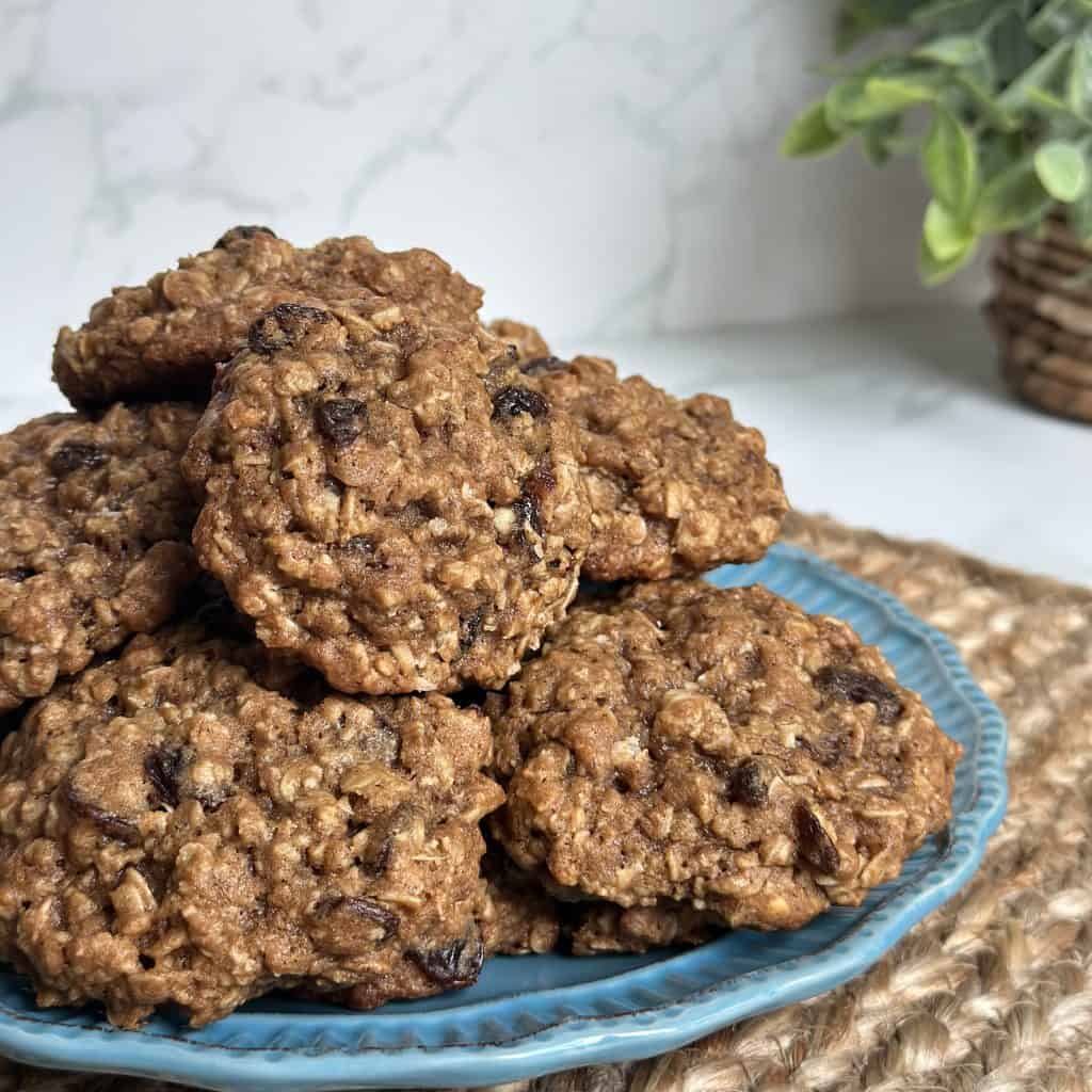 This is a picture of a blue plate topped with a pile of oatmeal raisin cookies.