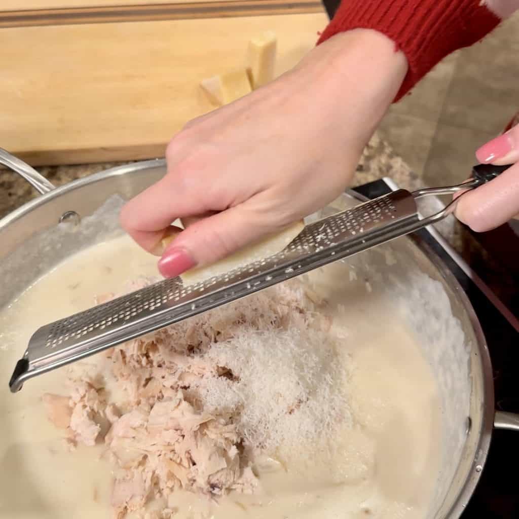 Grating parmesan cheese over the soup