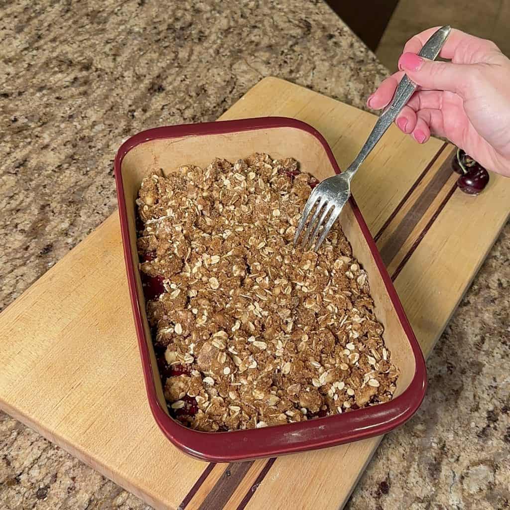 cherry pie filling covered by streusel in a baking dish