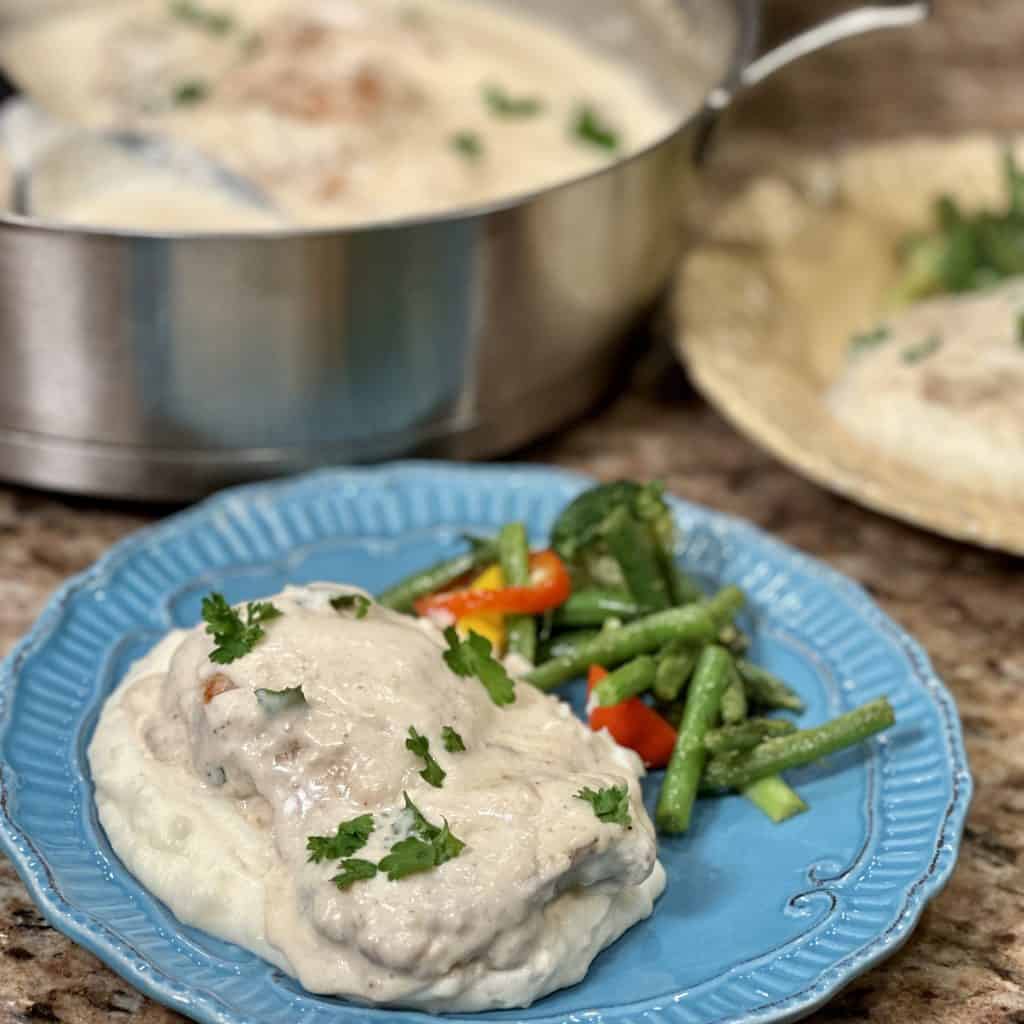 Garlic parmesan chicken served over mashed potatoes with vegetables on the side