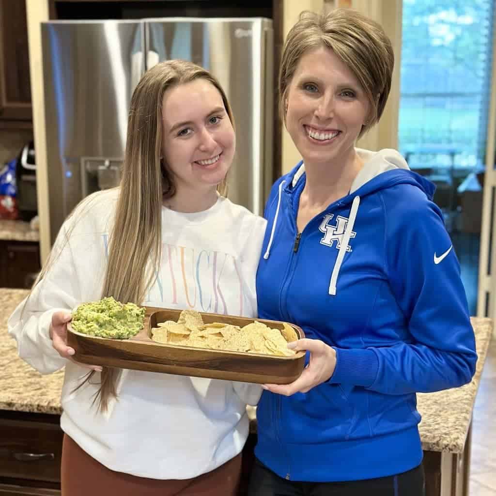 2 girls holding a tray of guacamole and chips.