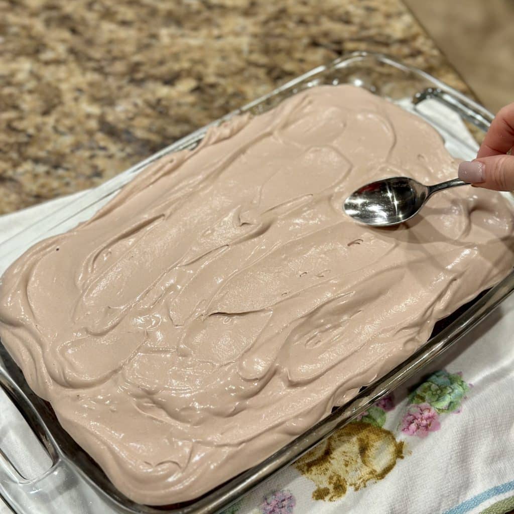 Spreading chocolate whipped topping over the cake