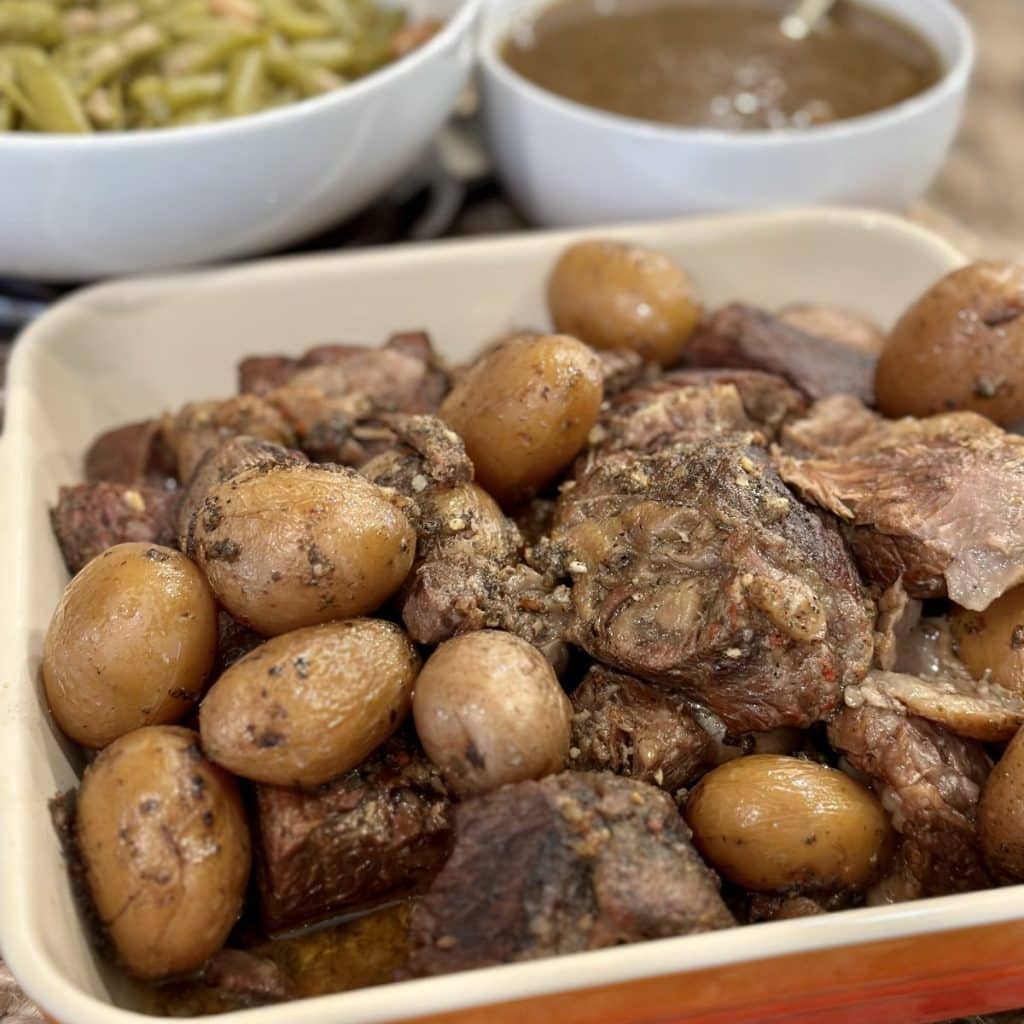 Cooked roast beef and potatoes with gravy and green beans on the side