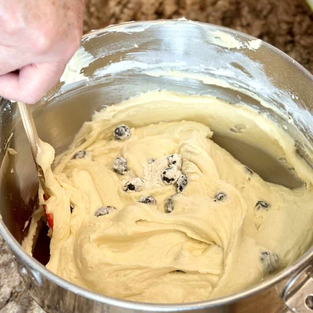 Folding blueberries in batter in a bowl.