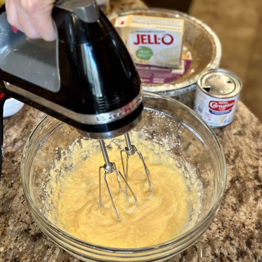 Mixer blending together a pudding mix and evaporated milk.