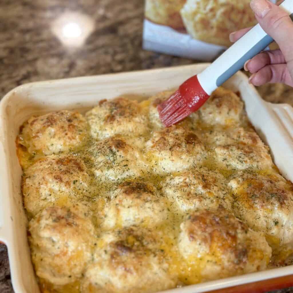 Brushing butter on Dolly Parton Stampede biscuits. 