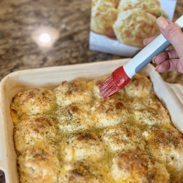 Biscuits being brushed with garlic butter.