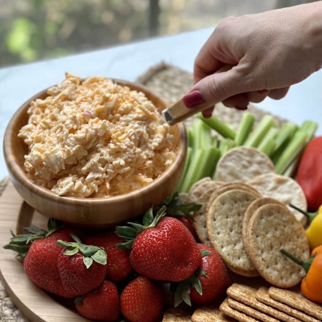 Pimento cheese in a bowl with fruits, veggies and crackers.