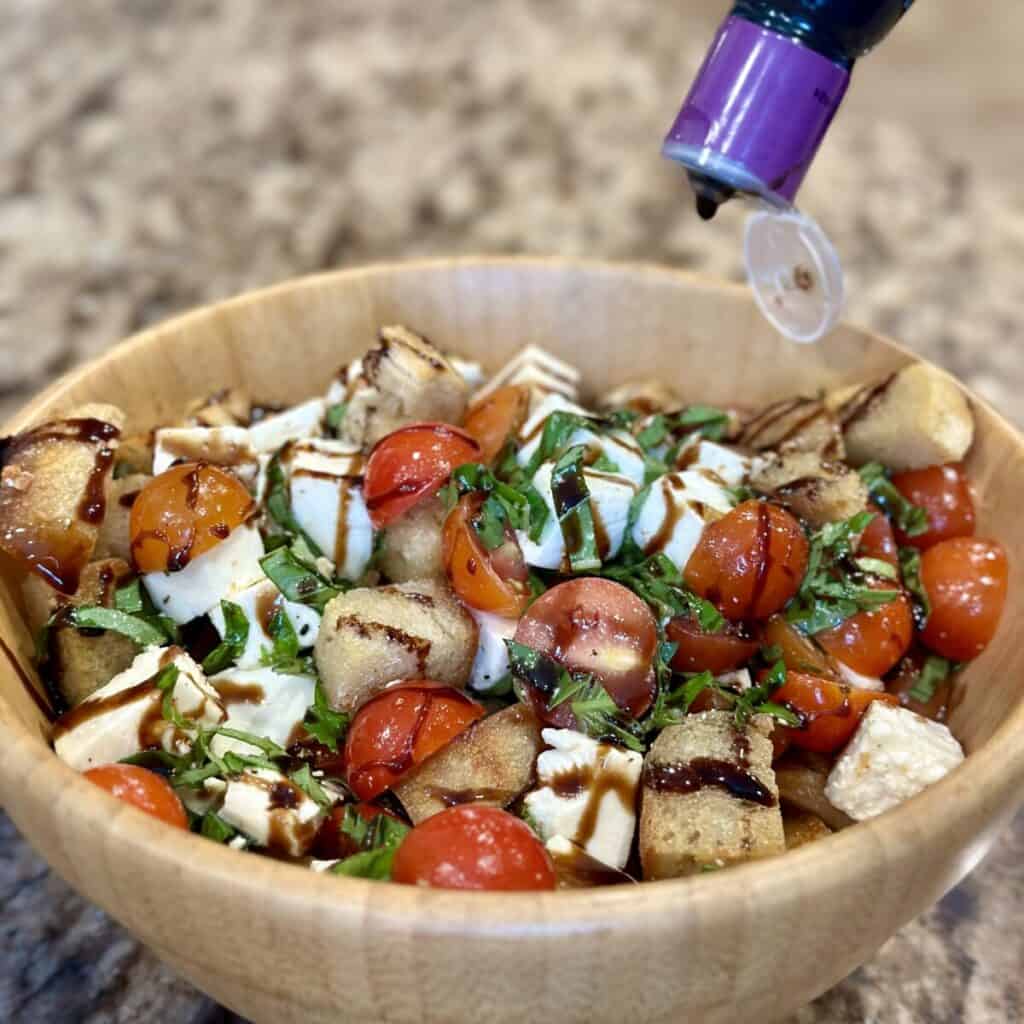 Drizzling balsamic glaze on panzanella.