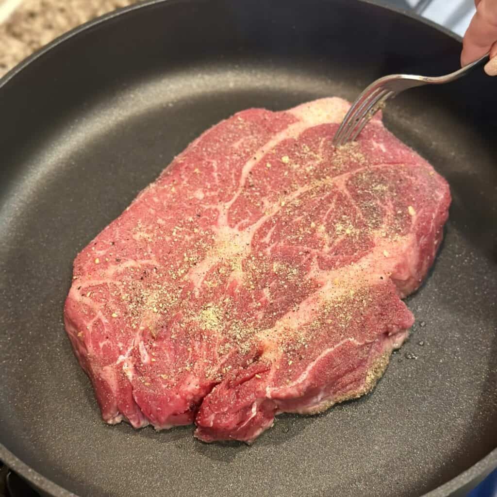 Searing a chuck roast in a pan.