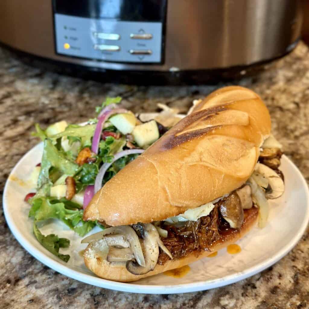 A bbq beef sandwich on a plate with a salad.